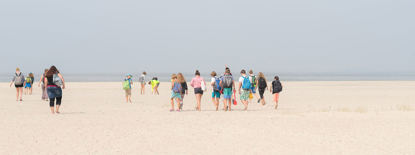 Eine Jugendgruppe geht über den weitläufigen Strand beim Haus Quellerdünen.