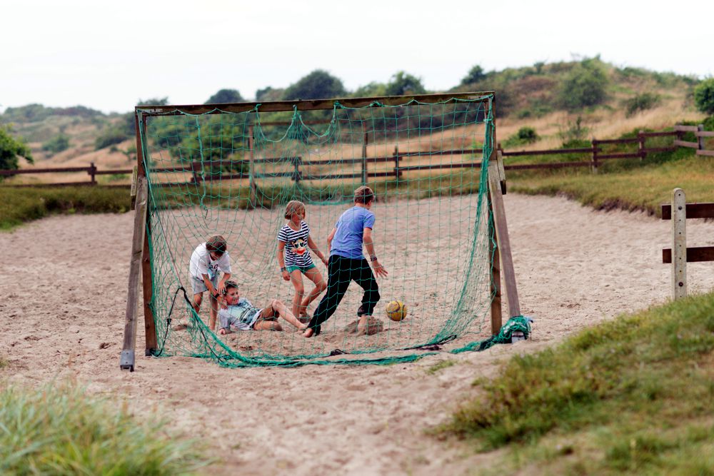Kinder spielen Fußball auf der Sandspielfläche